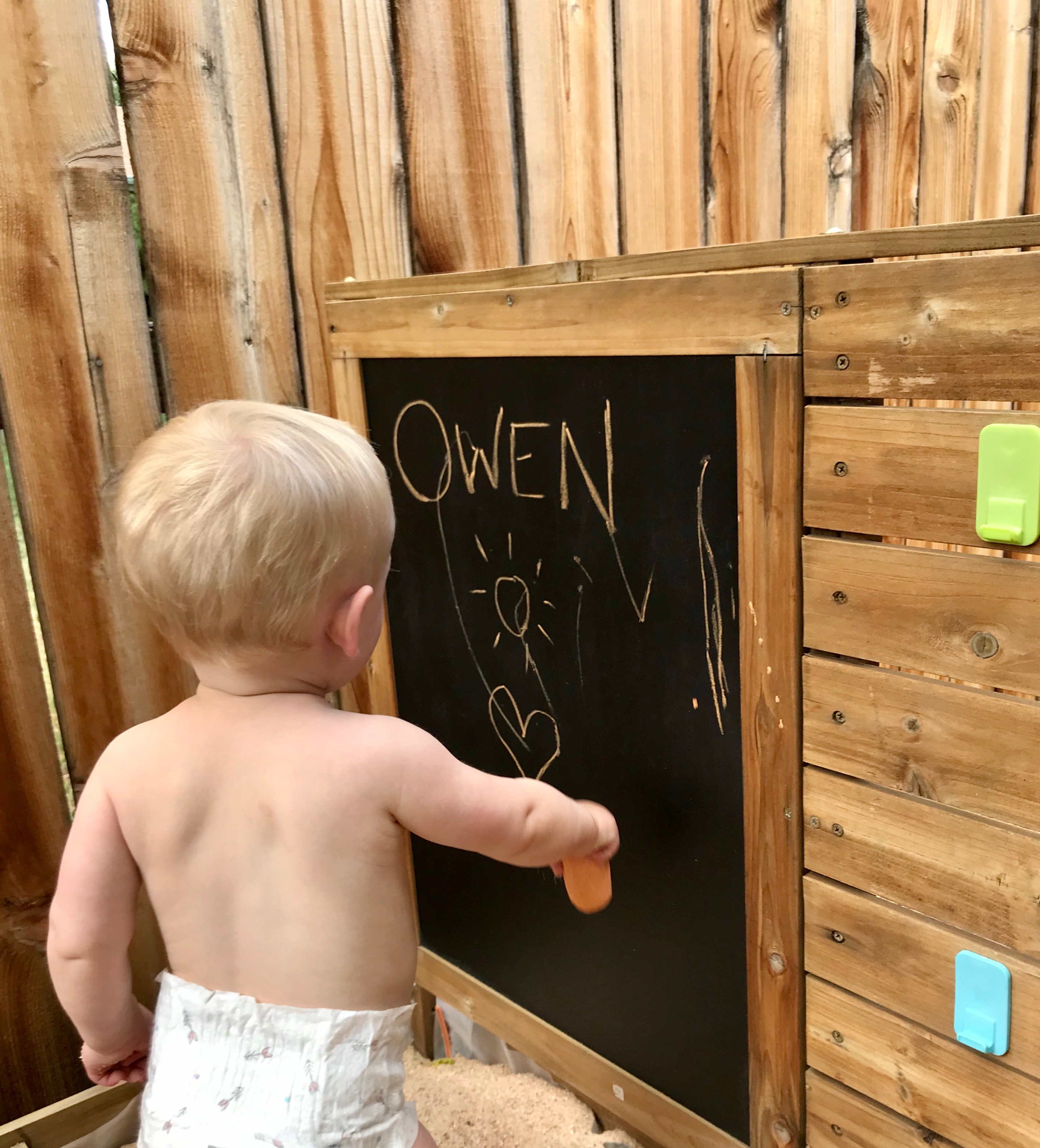 Owen writing with chalk in his sandbox.