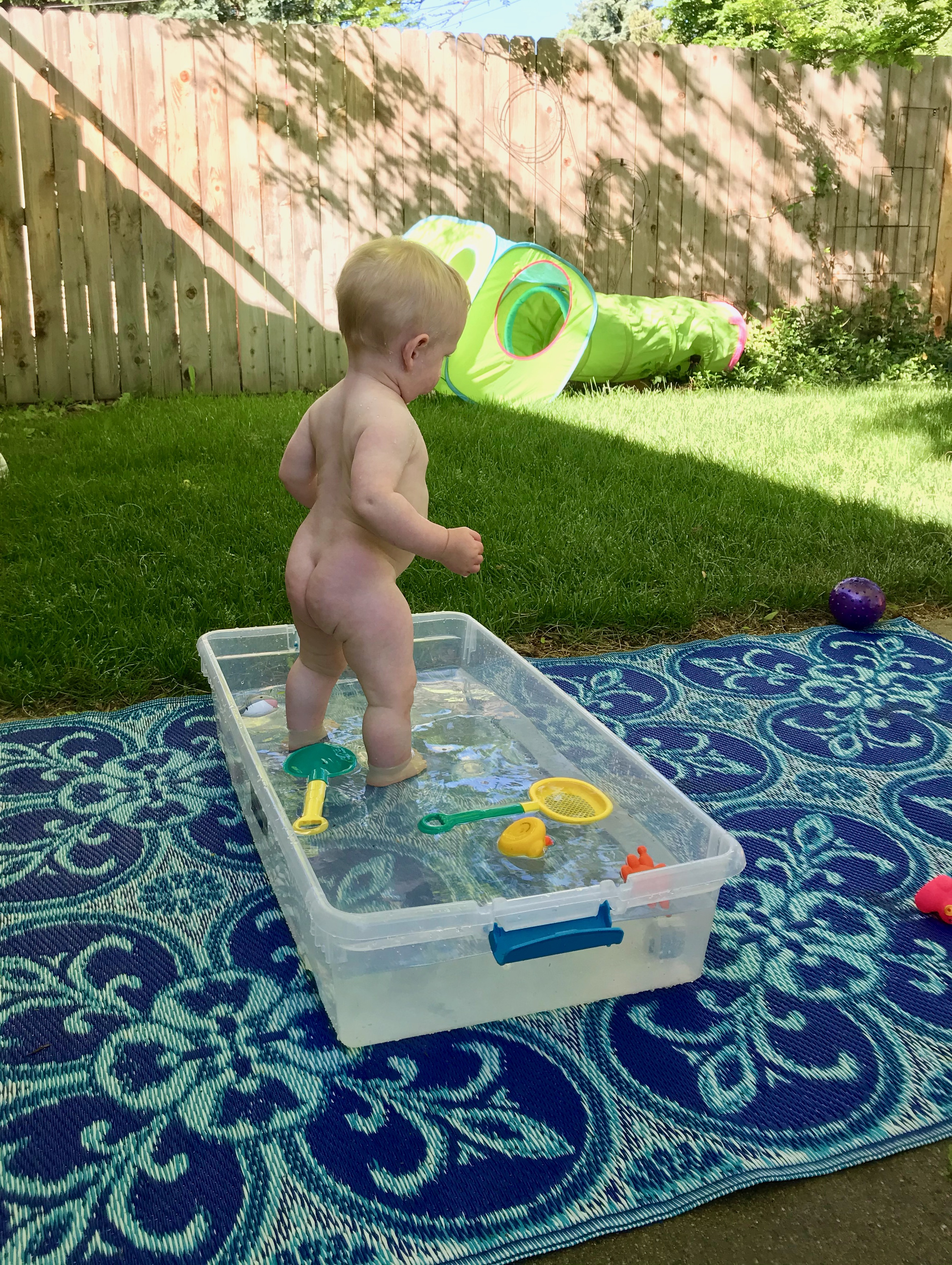 Owen playing with a makeshift wading pool in the back yard.