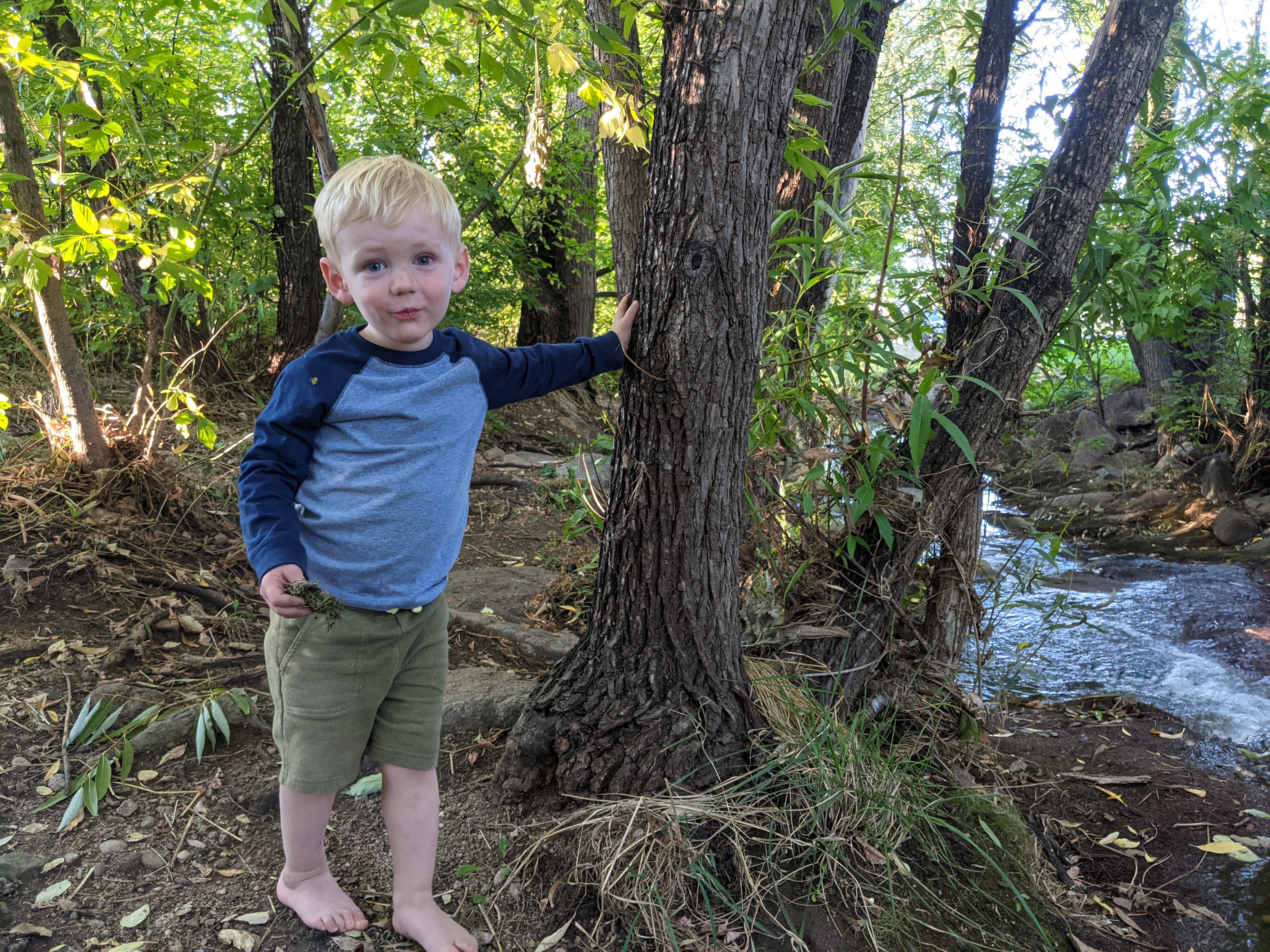 Owen leaning on a tree by the creek